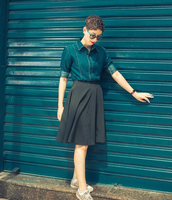 Woman in a calm yoga pose against a dark background with teal light.